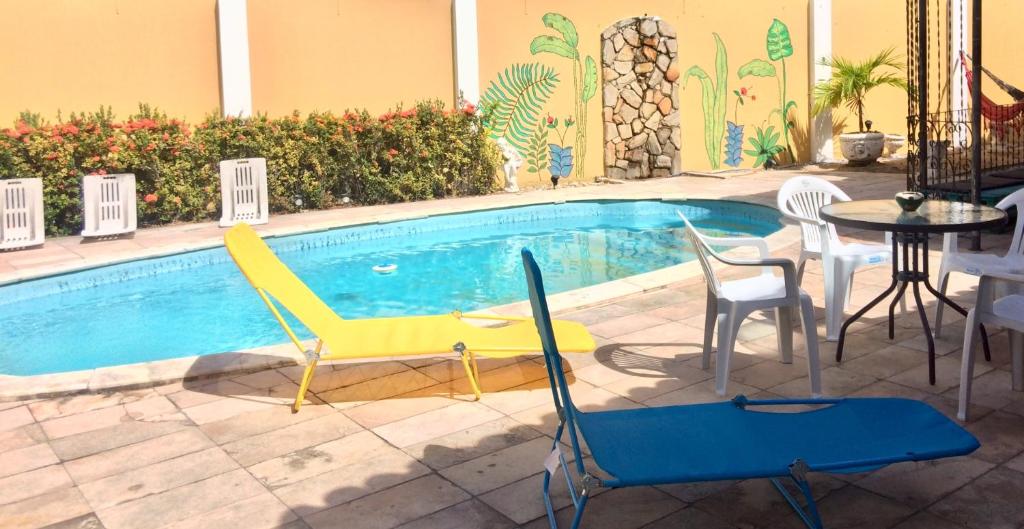 einen Pool mit Stühlen, einem Tisch und Stühlen in der Unterkunft Hostel Morais Praia in Maceió