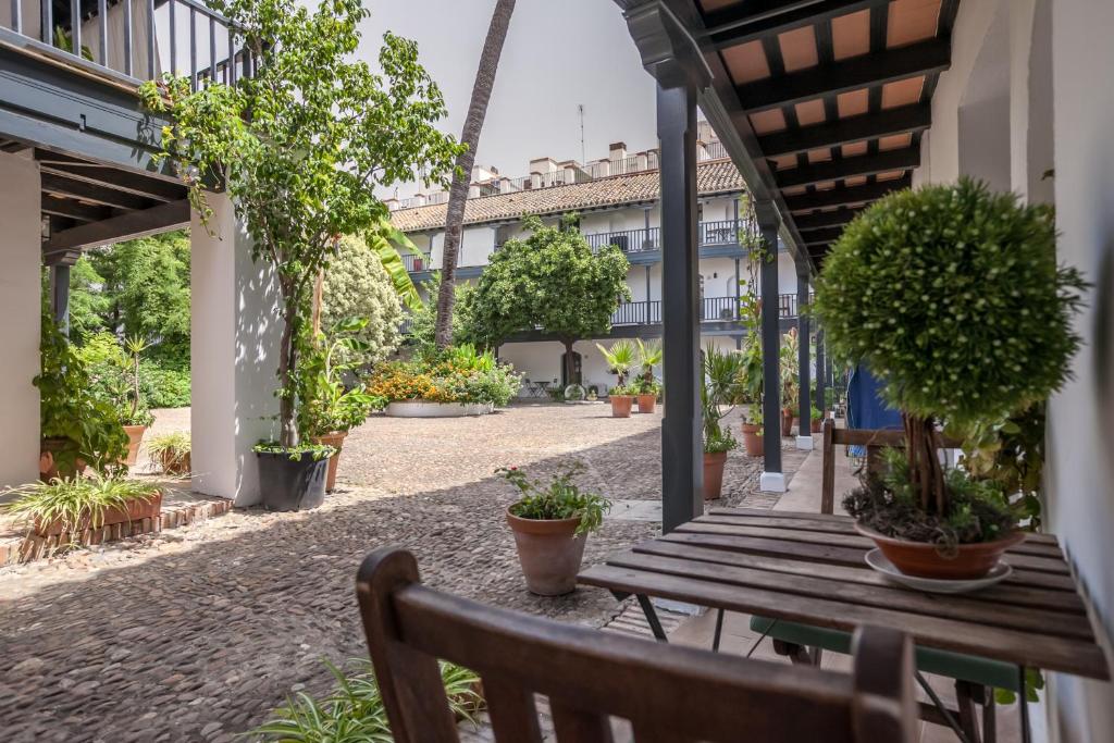 un patio vacío con banco de madera y macetas en Apartamentos Gadi Corral Siglo XVI en Sevilla