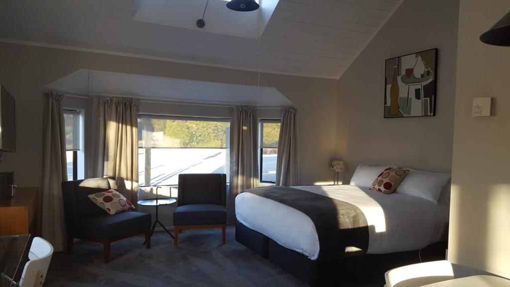 a bedroom with a bed and a chair and a window at The Ohakune Central Motels in Ohakune