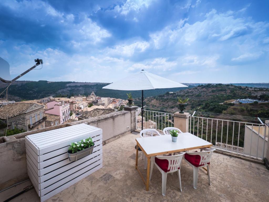 a table and chairs on a balcony with an umbrella at Casa Vacanze Al Duomo Ibla in Ragusa
