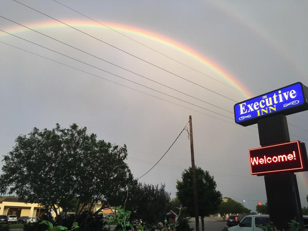 um arco-íris no céu com um sinal para uma estalagem excitante em The Executive Inn & Suites em Amarillo