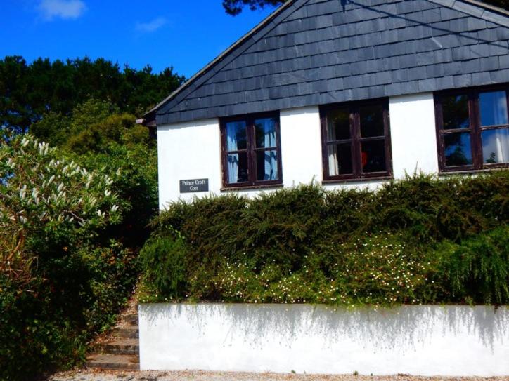 a white house with a black roof and windows at Prince Croft Cottage in Porthtowan