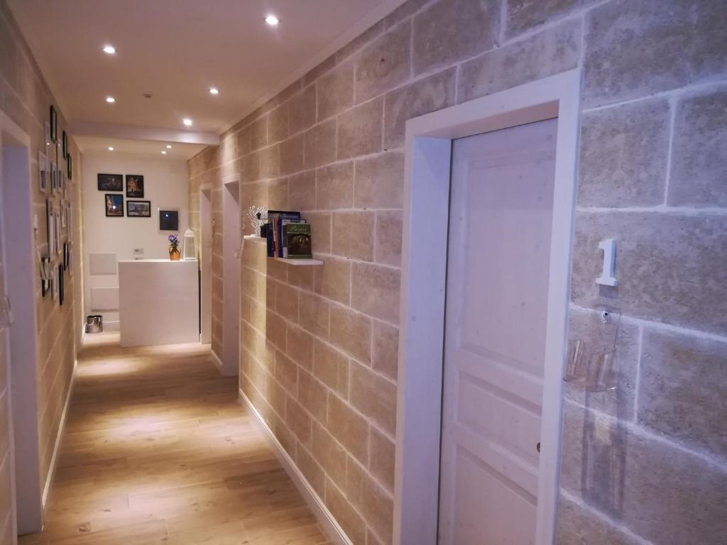 un pasillo con una pared de ladrillo y una puerta blanca en B&B Suites Via del Mare, en Presicce
