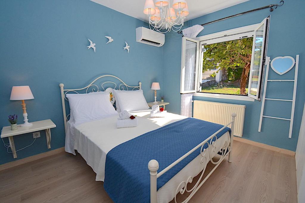 Dormitorio azul con cama y ventana en Villa Jasmine Blossom en Gouvia