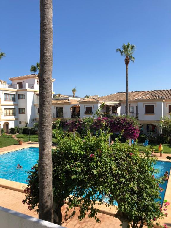 vistas a una piscina con palmeras y edificios en Apartamento EL PATIO V, en Denia