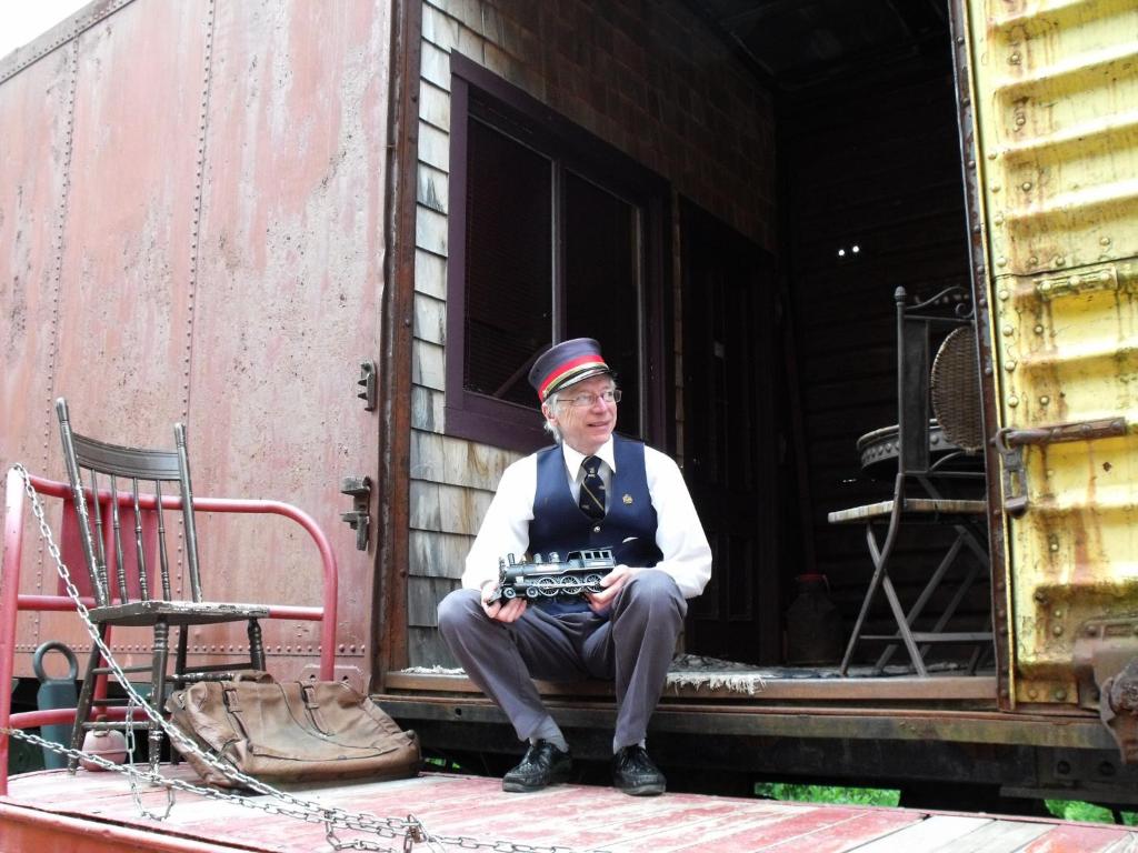 un hombre sentado en la puerta de un vagón de tren en Train Station Inn, en Tatamagouche