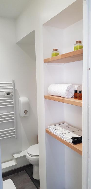 a white bathroom with a toilet and shelves at Val&#39; Appart 1 in Valenciennes