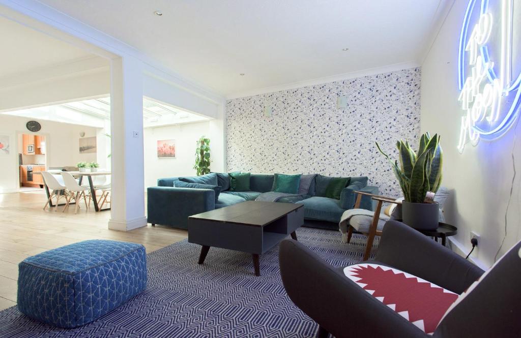 a living room with a blue couch and a table at The Harrods Mews - Modern 4BDR + Rooftop & Garage in London