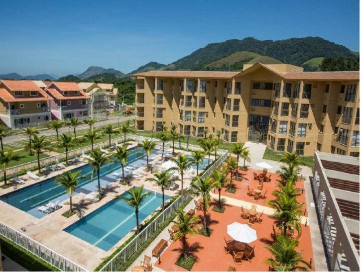 an aerial view of a resort with a pool and palm trees at Loft Condado em Sahy - Mangaratiba in Mangaratiba