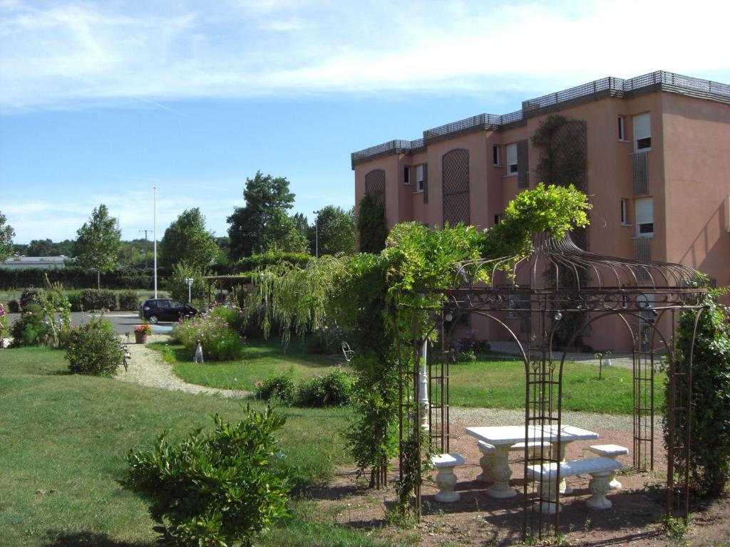 un jardín con cenador con banco y un edificio en Hotel Au Sans Souci en Chinon