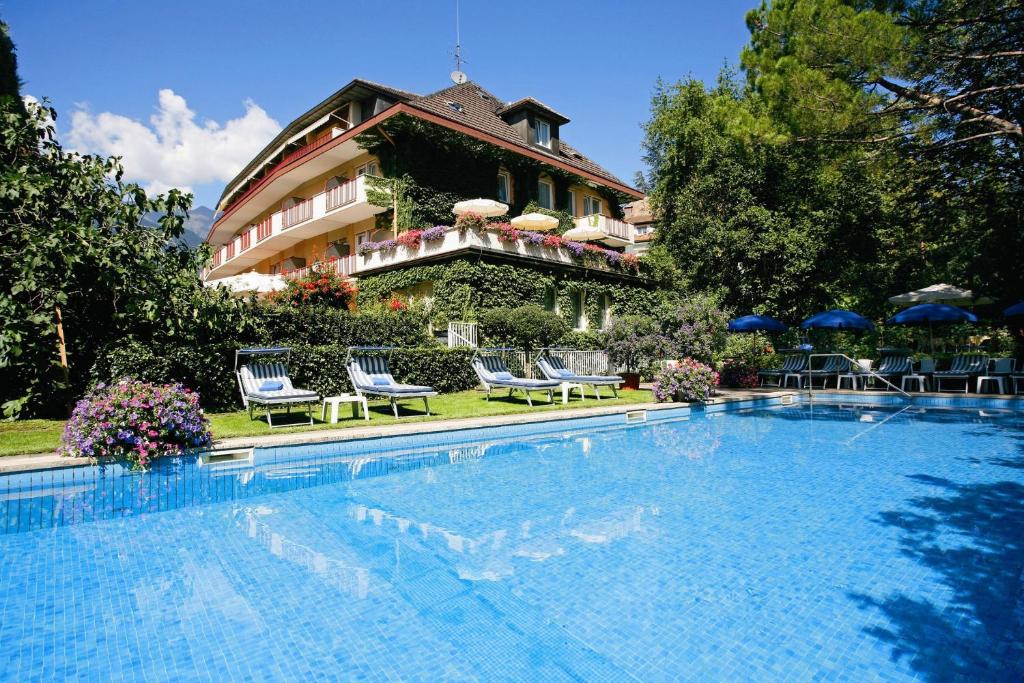 un hotel con piscina di fronte a un edificio di Hotel Juliane a Merano