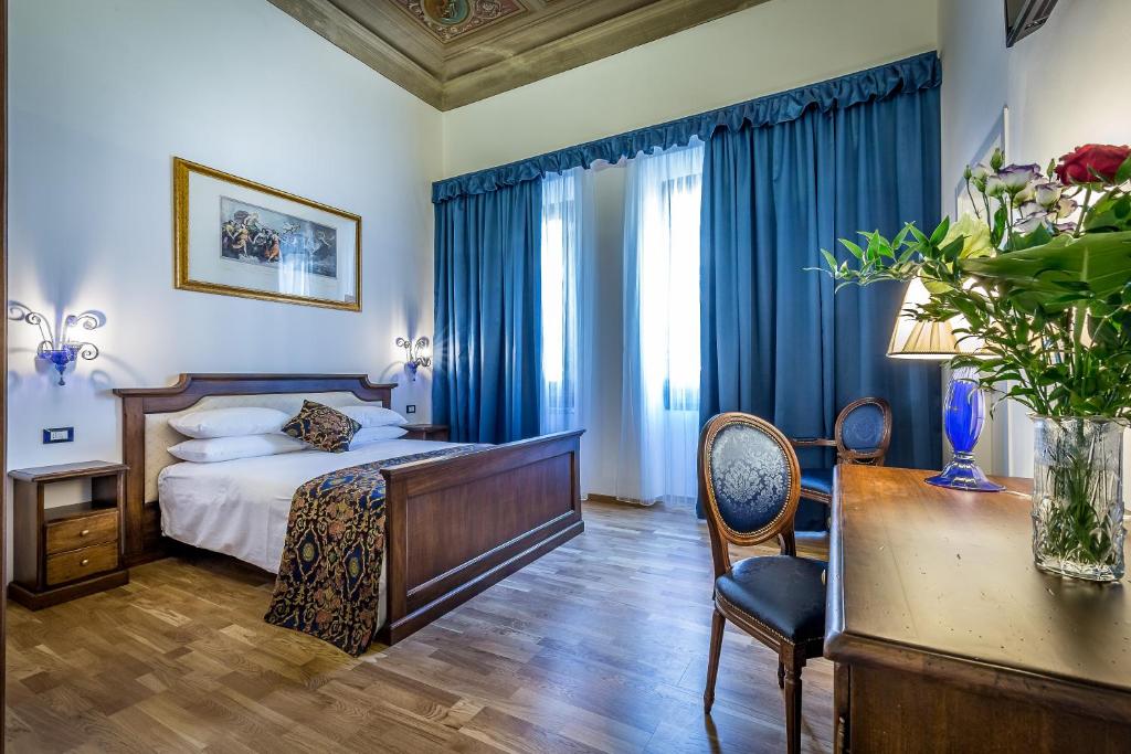 a bedroom with a bed with blue curtains and a desk at HomEdo B&B in Florence