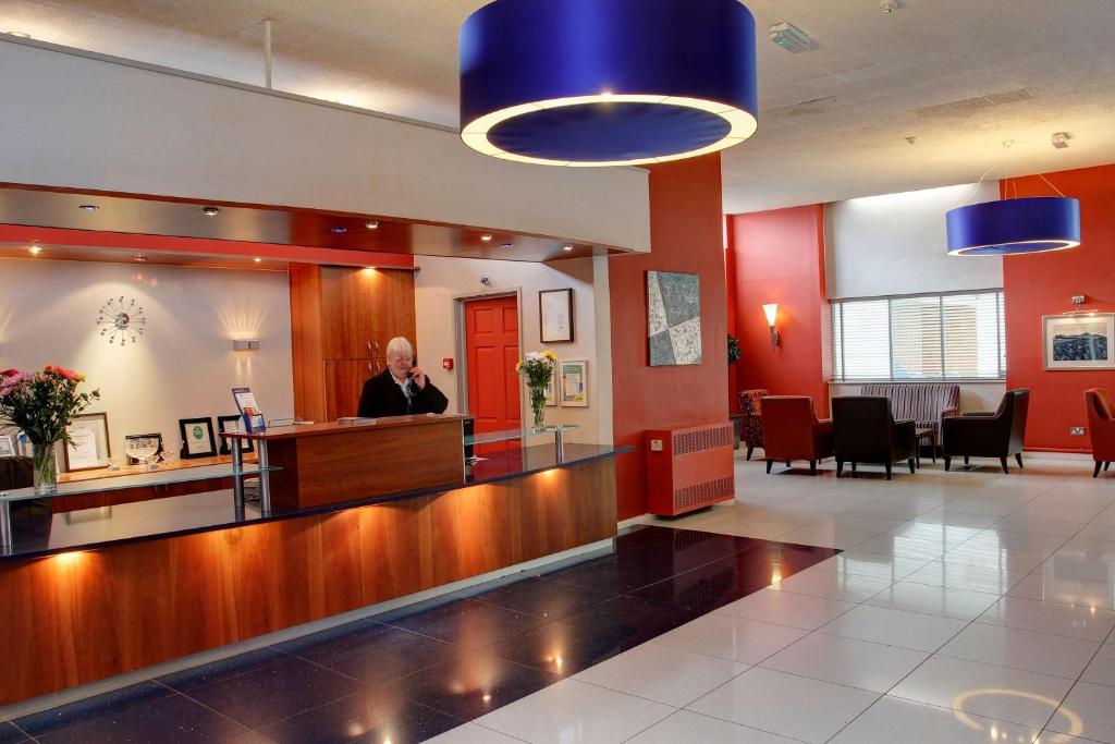 a man standing at a reception desk in a waiting room at Best Western Aberavon Beach Hotel in Port Talbot