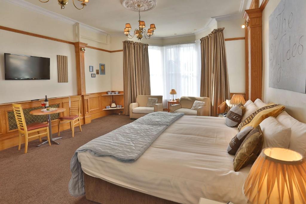 a bedroom with a large bed and a living room at Best Western Woodlands Hotel in Dundee