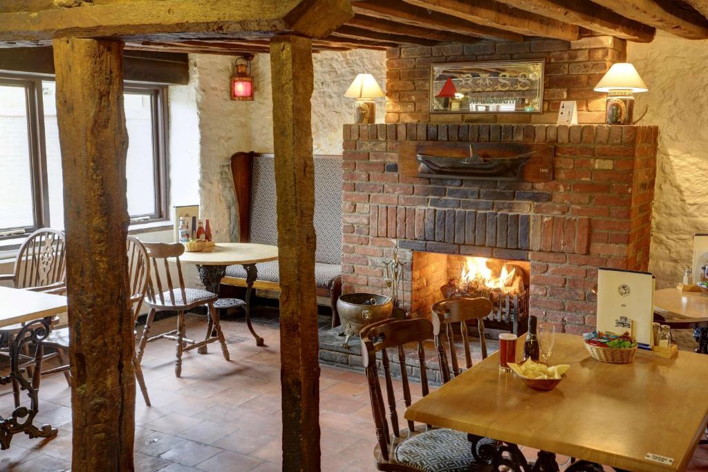 a fireplace in a restaurant with tables and chairs at Old Hunstanton Le Strange Arms Hotel in Hunstanton