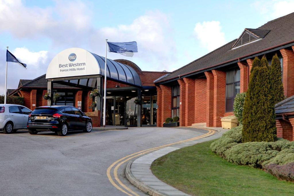 a building with two cars parked in a parking lot at Best Western Frodsham Forest Hills Hotel in Frodsham