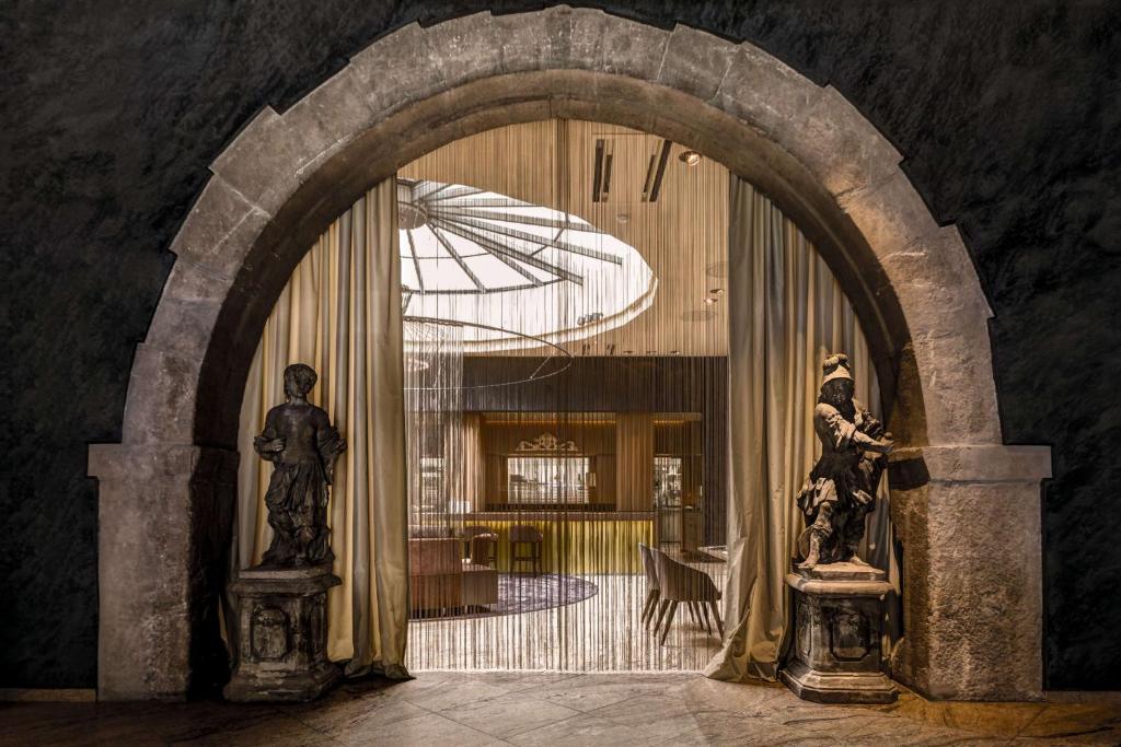 a hallway with an archway with an umbrella and two statues at Best Western Premier Hotel Rebstock in Würzburg