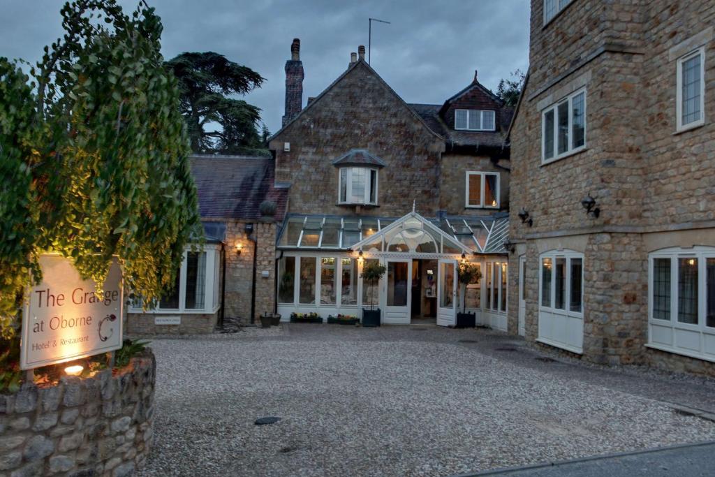 a large brick building with a sign in front of it at The Grange at Oborne in Sherborne