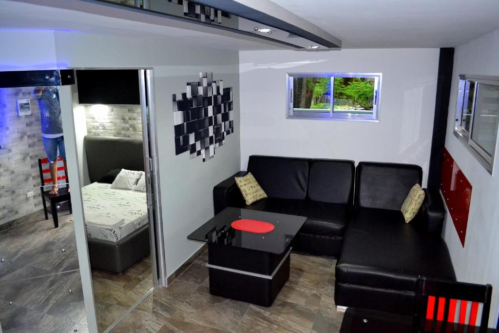 ein Wohnzimmer mit einem schwarzen Sofa und einem Tisch in der Unterkunft Micky Santoro -Apartments in Bantayan