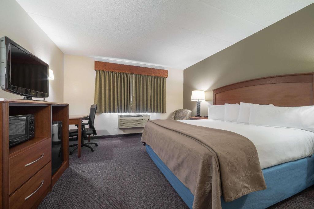 a hotel room with a bed and a desk and a television at AmericInn by Wyndham Hutchinson in Hutchinson