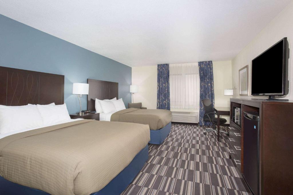 a hotel room with two beds and a flat screen tv at AmericInn by Wyndham Mount Pleasant in Mount Pleasant