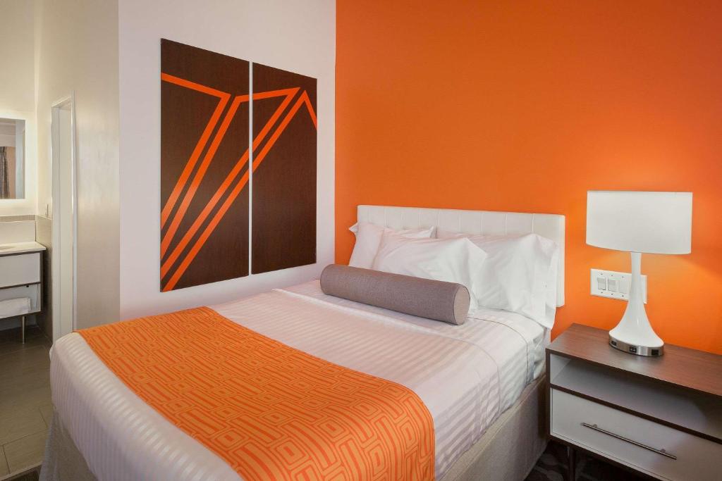 um quarto com uma cama com uma parede laranja em Howard Johnson by Wyndham Toms River em Toms River