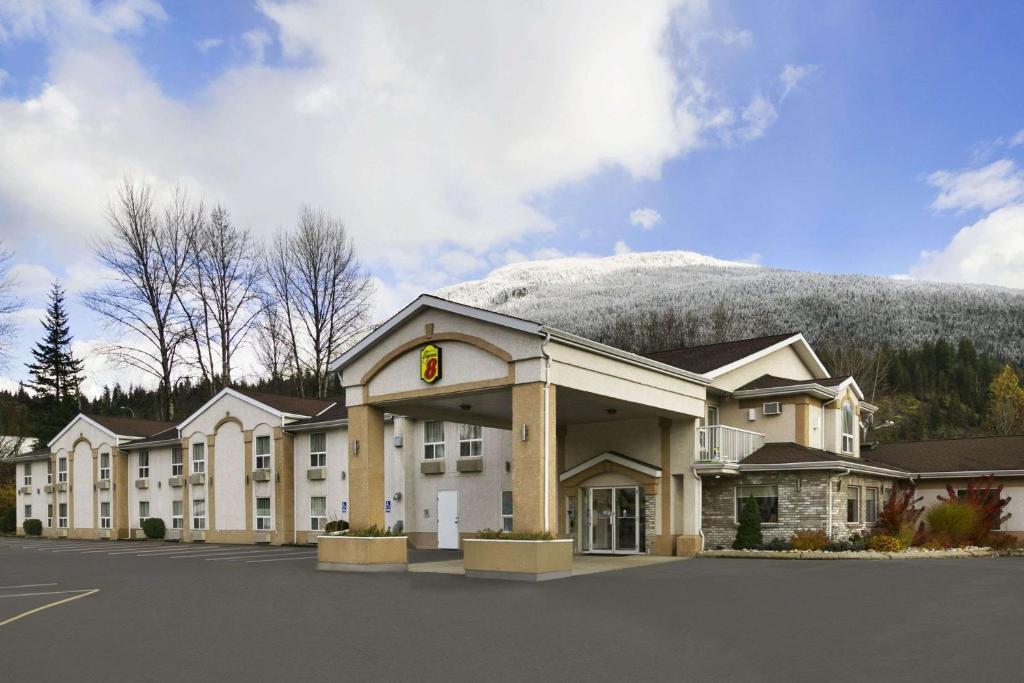 a hotel building with a mountain in the background at Super 8 by Wyndham Revelstoke BC in Revelstoke