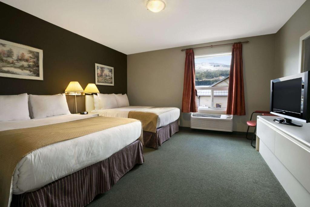 a hotel room with two beds and a flat screen tv at Super 8 by Wyndham Revelstoke BC in Revelstoke