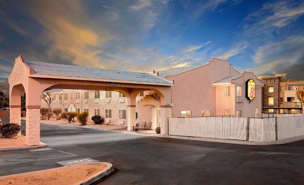 a parking lot with a large building with a fence at Super 8 by Wyndham Yucca Val/Joshua Tree Nat Pk Area in Yucca Valley