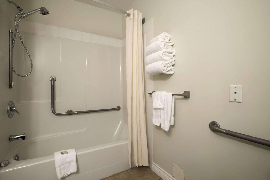 a bathroom with a shower and a bath tub with towels at Super 8 by Wyndham Revelstoke BC in Revelstoke