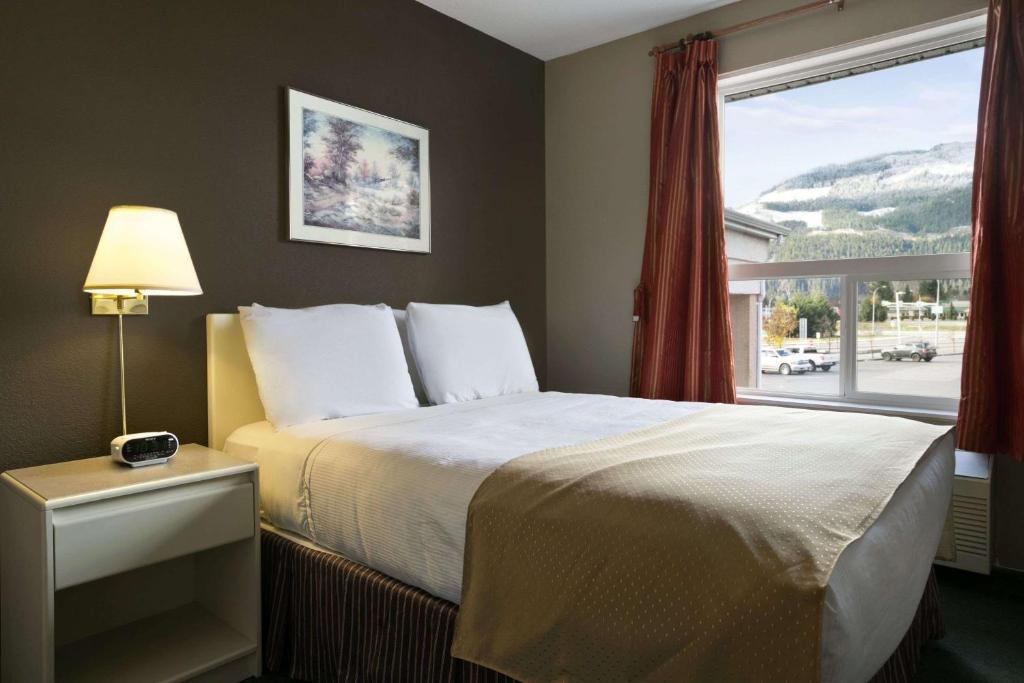 a bedroom with a bed and a large window at Super 8 by Wyndham Revelstoke BC in Revelstoke