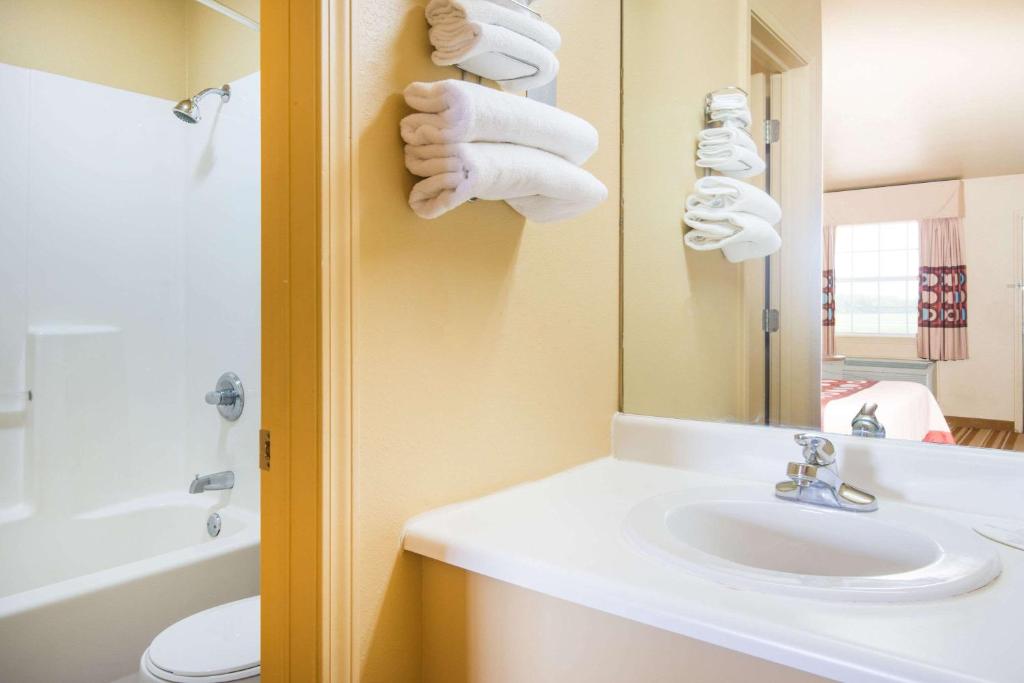 a bathroom with a sink and a mirror and towels at Super 8 by Wyndham Big Cabin/Vinita Area in Vinita