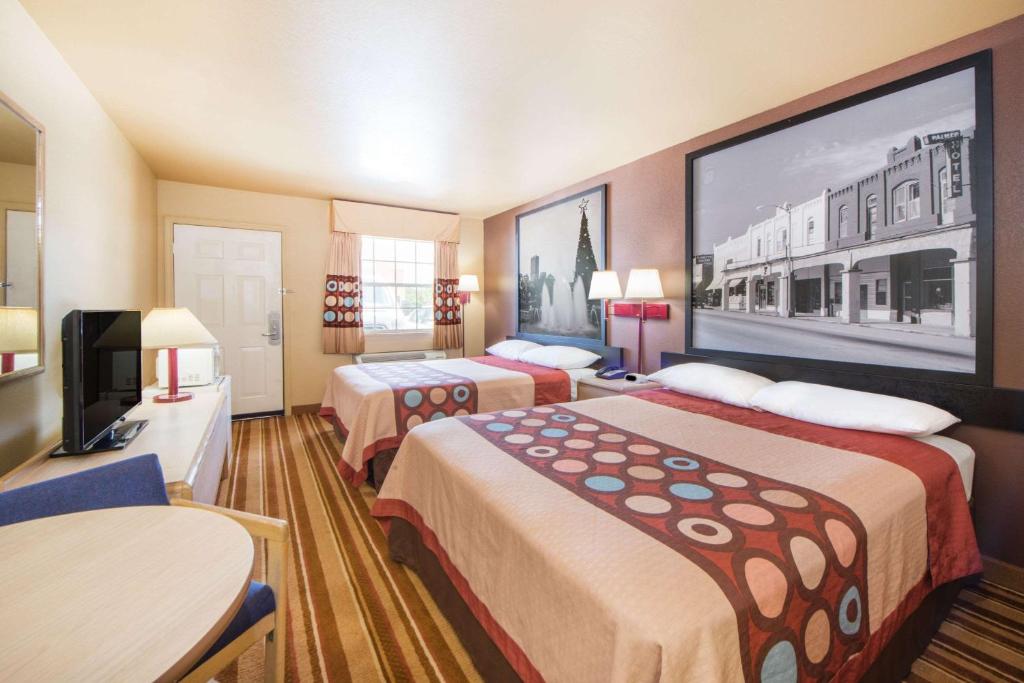 a hotel room with two beds and a flat screen tv at Super 8 by Wyndham Big Cabin/Vinita Area in Vinita
