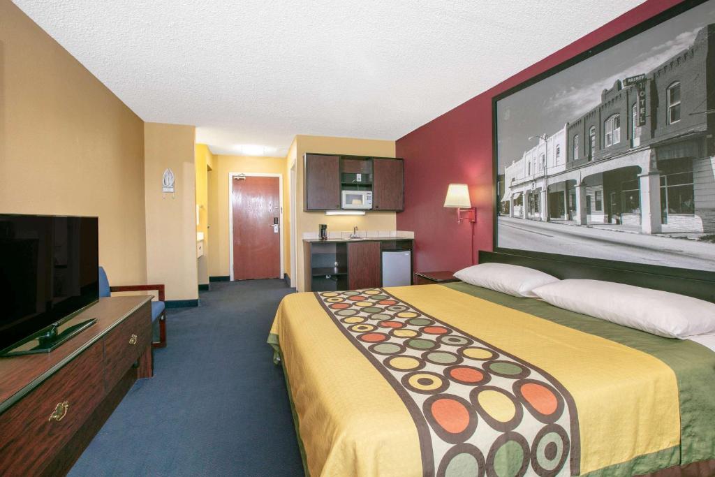 a hotel room with a large bed and a flat screen tv at Super 8 by Wyndham Big Cabin/Vinita Area in Vinita