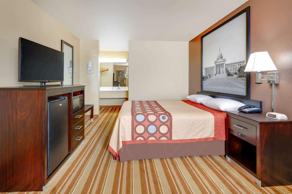 a hotel room with a bed and a flat screen tv at Super 8 by Wyndham Big Cabin/Vinita Area in Vinita