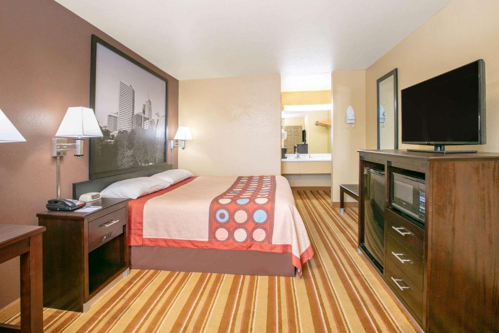 a hotel room with a bed and a flat screen tv at Super 8 by Wyndham Big Cabin/Vinita Area in Vinita
