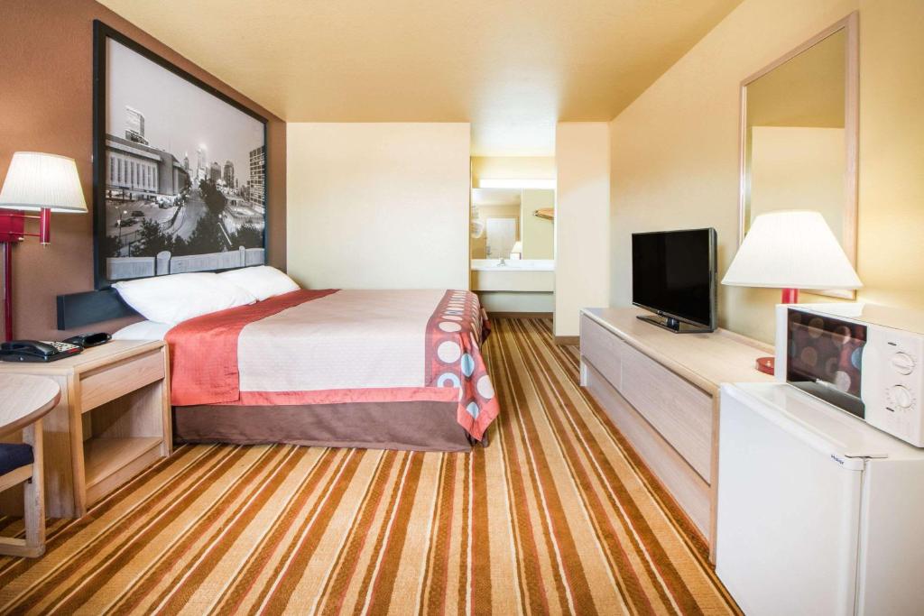 a hotel room with a bed and a flat screen tv at Super 8 by Wyndham Big Cabin/Vinita Area in Vinita