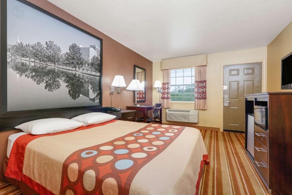 a hotel room with a bed and a large screen at Super 8 by Wyndham Big Cabin/Vinita Area in Vinita