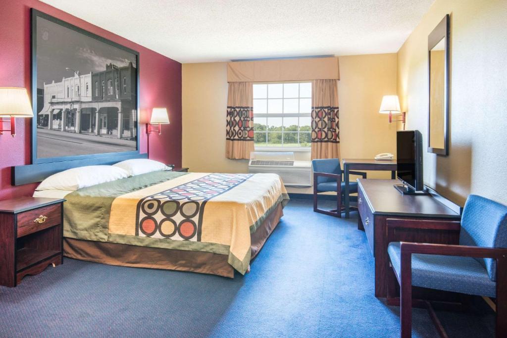 a hotel room with a bed and a desk and a computer at Super 8 by Wyndham Big Cabin/Vinita Area in Vinita