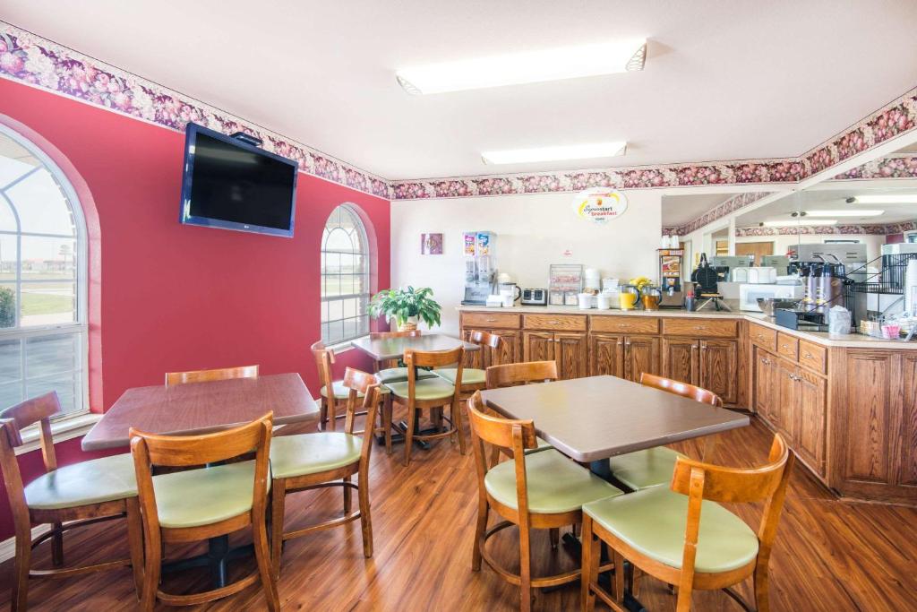 a restaurant with tables and chairs and a kitchen at Super 8 by Wyndham Big Cabin/Vinita Area in Vinita