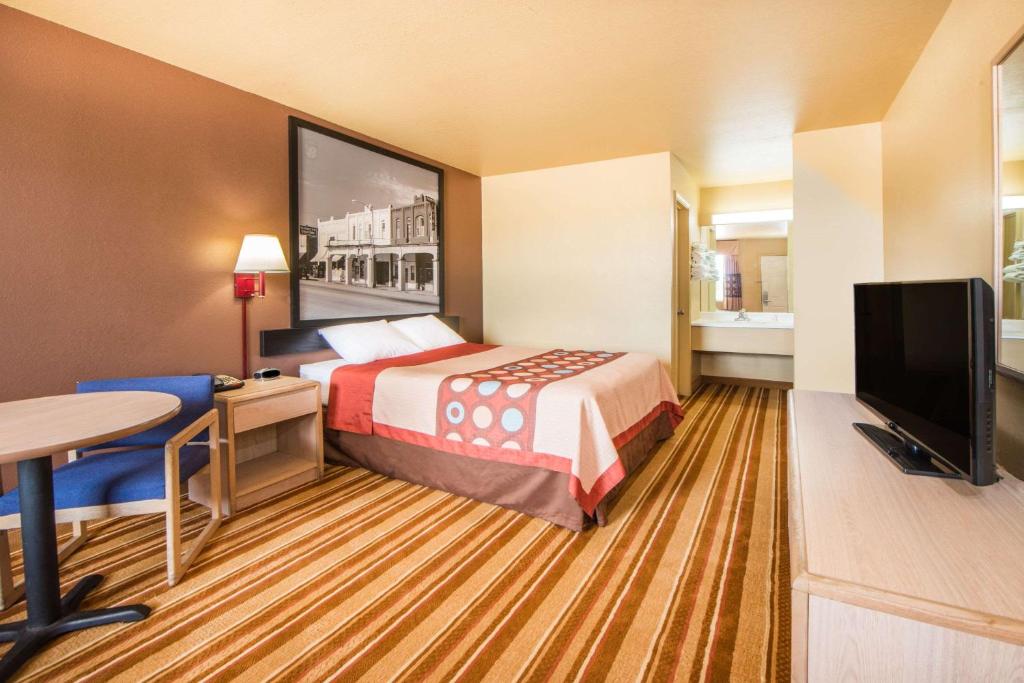 a hotel room with a bed and a flat screen tv at Super 8 by Wyndham Big Cabin/Vinita Area in Vinita