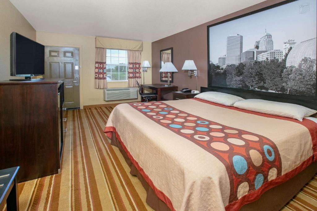 a hotel room with a large bed and a flat screen tv at Super 8 by Wyndham Big Cabin/Vinita Area in Vinita