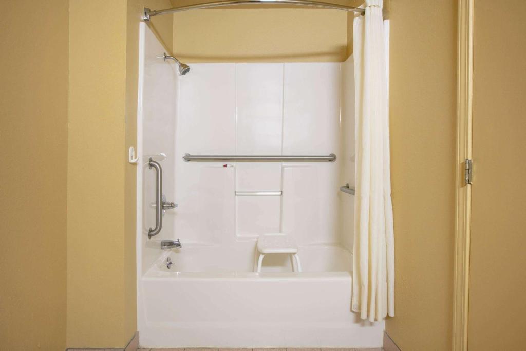 a bathroom with a white tub and a shower at Super 8 by Wyndham Big Cabin/Vinita Area in Vinita