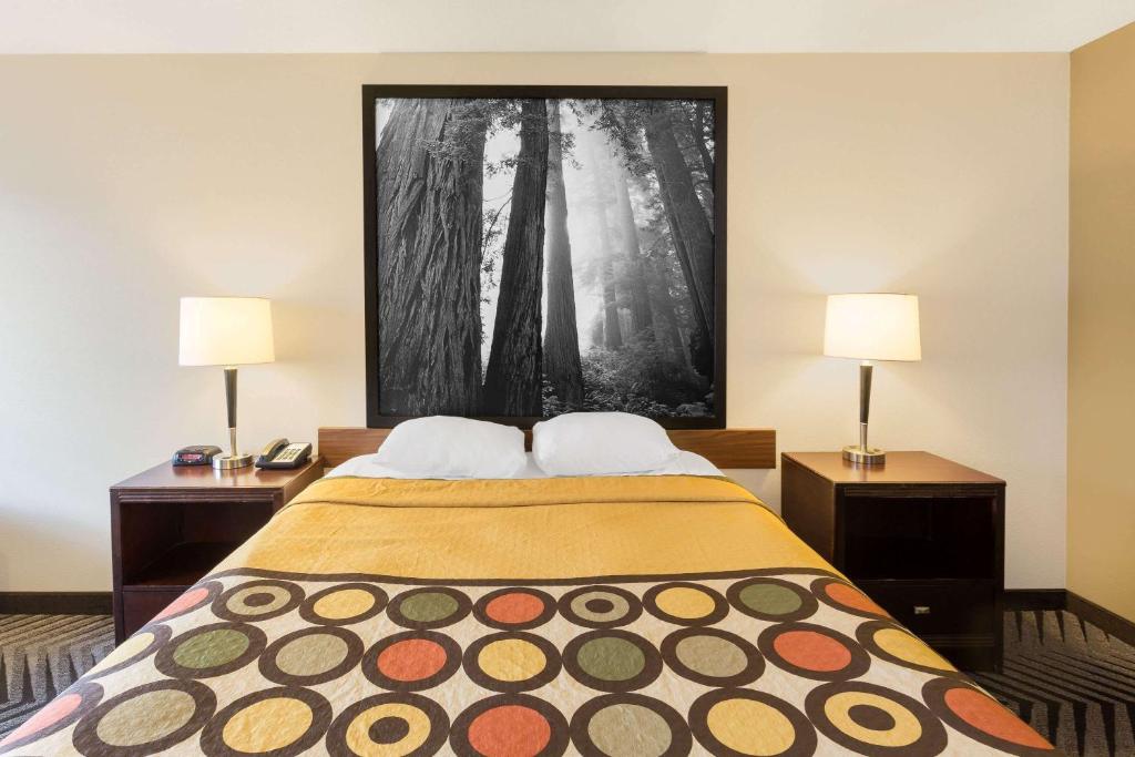 a bedroom with a bed with two lamps and a painting on the wall at Super 8 by Wyndham Fortuna in Fortuna