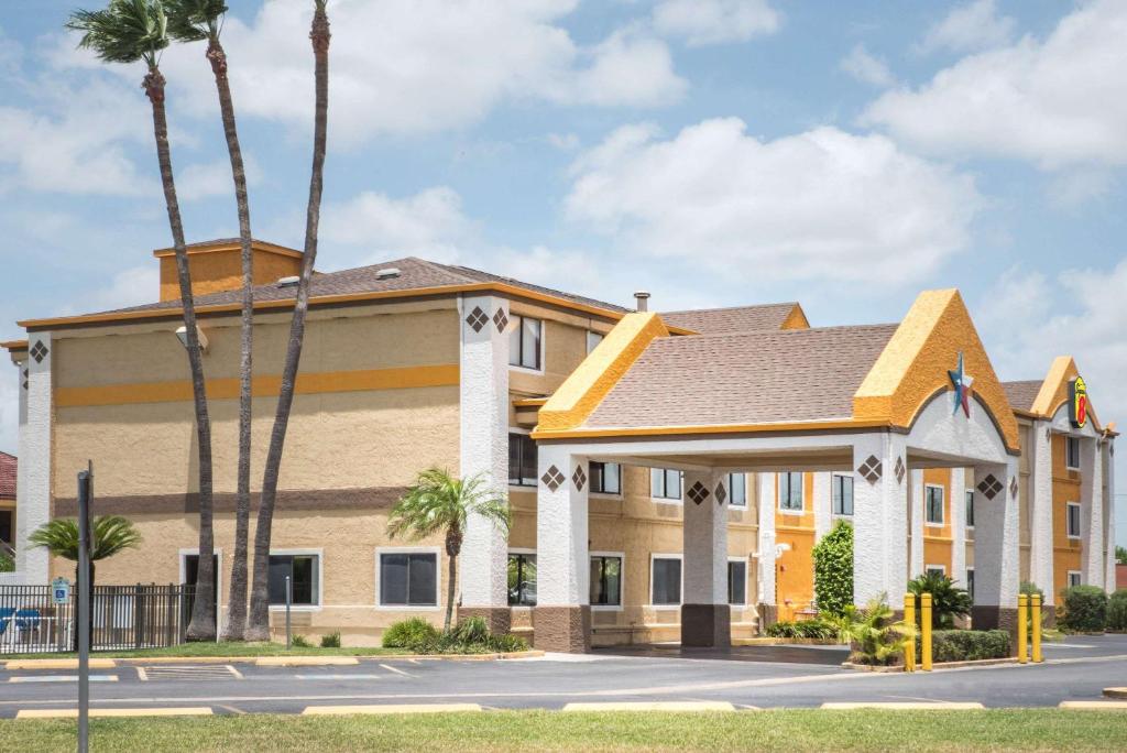 Un edificio con palmeras frente a una calle. en Super 8 by Wyndham Harlingen TX, en Harlingen