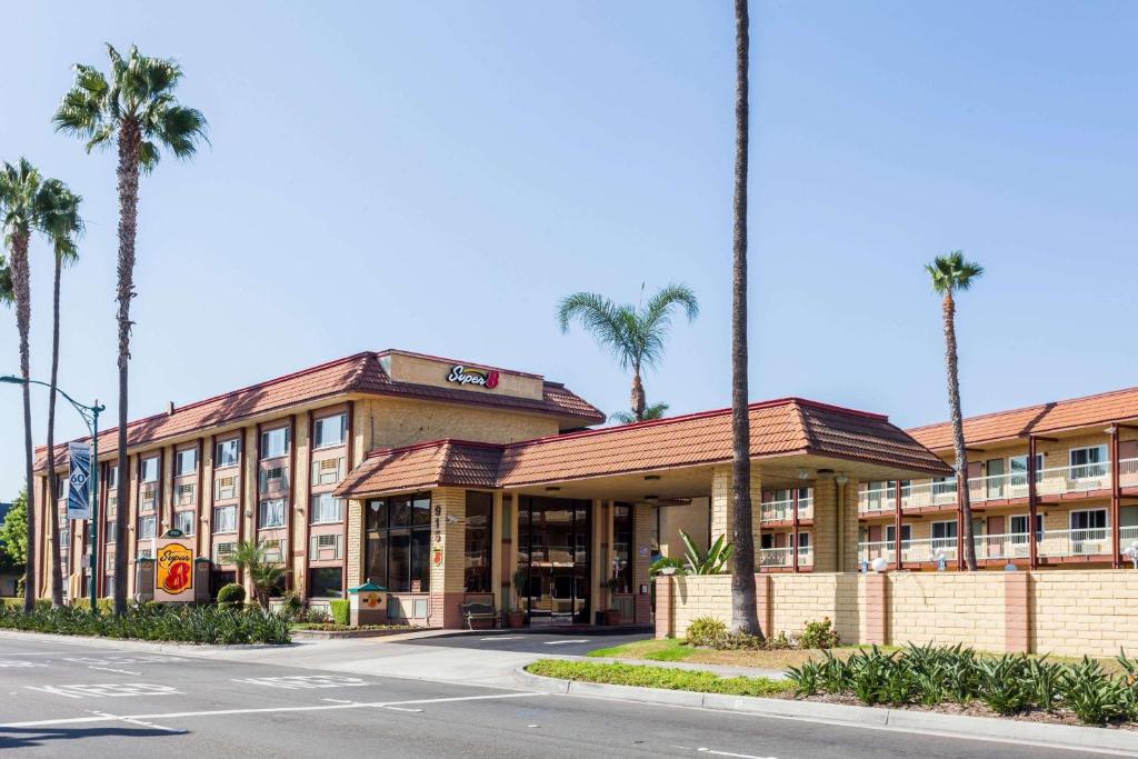 a building with palm trees in front of a street at Super 8 by Wyndham Anaheim/Disneyland Drive in Anaheim