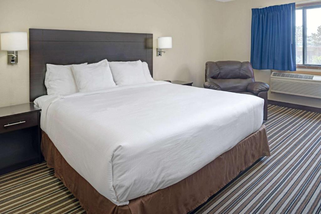 a hotel room with a large bed and a chair at Super 8 by Wyndham Omaha I-80 West in Millard