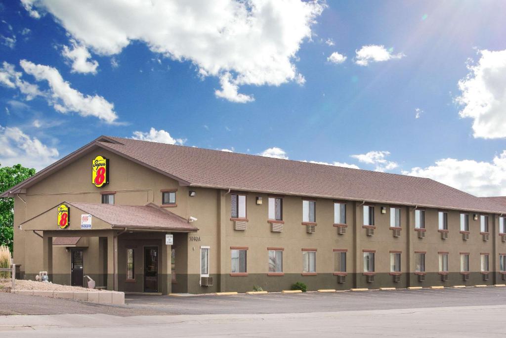 a large tan building with a red sign on it at Super 8 by Wyndham Colby in Colby