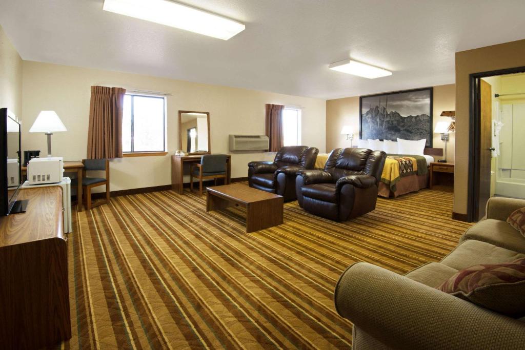 a hotel room with a bed and a living room at Super 8 by Wyndham Las Cruces/White Sands Area in Las Cruces