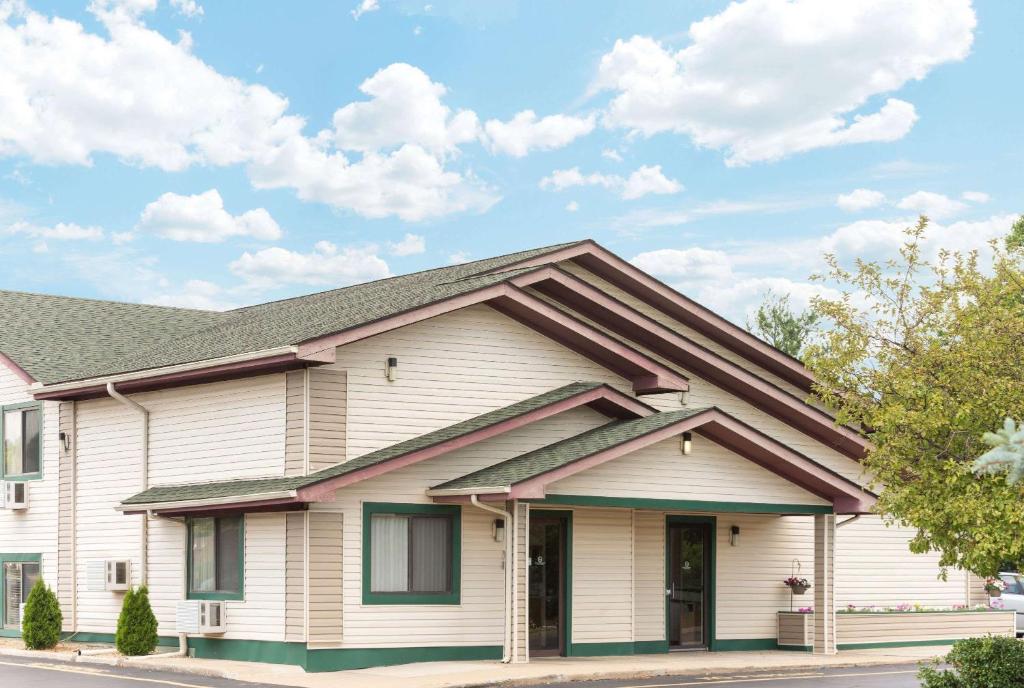 une maison blanche avec un toit marron dans l'établissement Super 8 by Wyndham Twinsburg/Cleveland Area, à Twinsburg